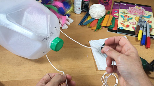 Yarn is threaded through holes in the top of the container to create a handle.