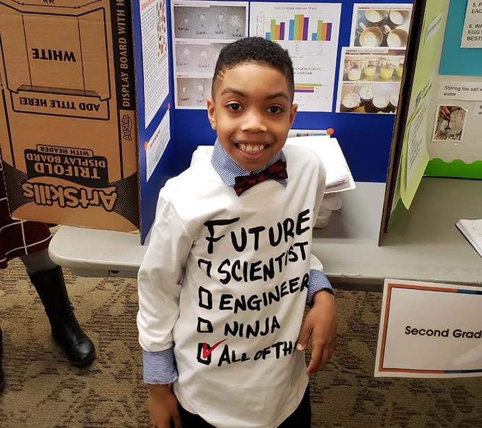 Student with his second-grade project display board from the science fair.
