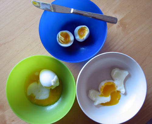 Three eggs cooked using a variety of soft-boiling methods, results ranging from very runny yolk to thick and viscous yolk.