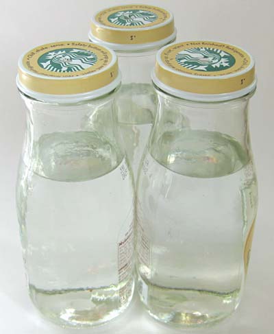Three bottles with water, touching, arranged in a triangle.
