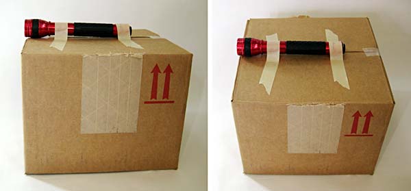 A flashlight taped to the top of a cardboard box.