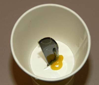 A plastic knife sticks up through the bottom of a paper cup and is glued in place