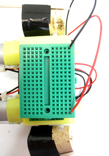 Wires from a battery pack are connected to a mini breadboard