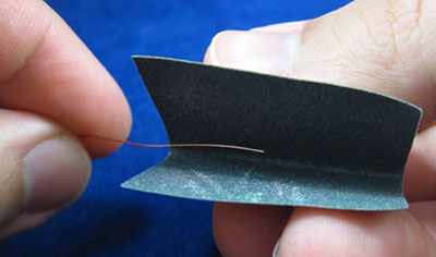 Stripping the insulation of a copper wire with sandpaper