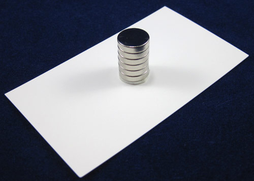 Double sided tape holds a stack of circular magnets to the center of a business card