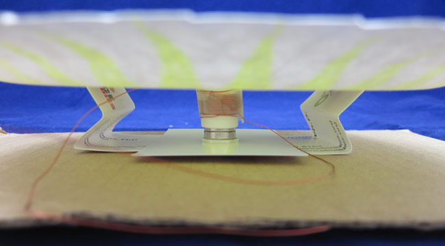 A stack of magnets is inserted into a paper tube wrapped in copper wire that is glued to the bottom of a paper plate