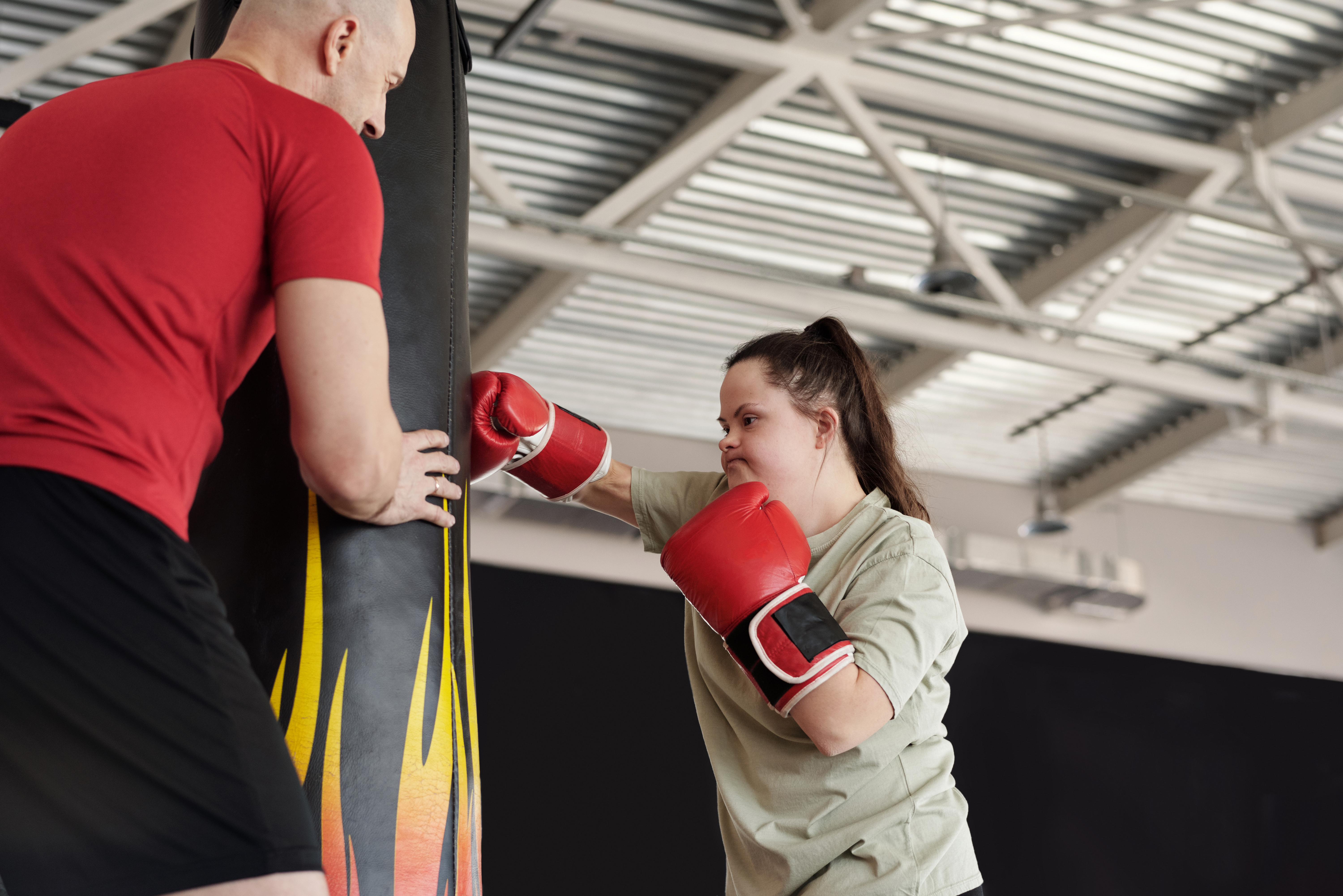 Female athletic trainer helping woman lift weights.