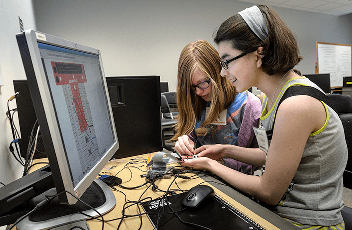 Two students doing hands-on Raspberry Pi projects and inserting electronics components in a breadboard