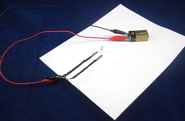 A paper circuit made from a battery, alligator clips, electric paint and an LED