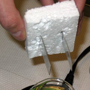 another view of Two strips of metal stick through a block of styrofoam 