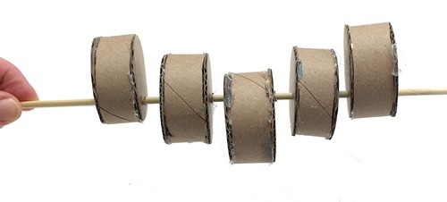 A skewer with five cylinders threaded on it. The cylinders are alternatingly placed on and off center, starting with an off-center cylinder.