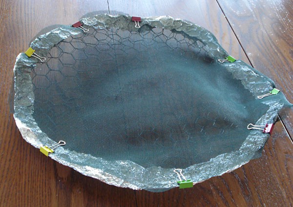 Chicken wire and mesh are cut into a large circle and held together with aluminum foil and binder clips