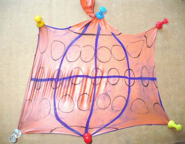 the cut open balloon pinned down  with 6 pins to form almost a square.  Some circles are deformed. Cricles away from the equator are larger. 