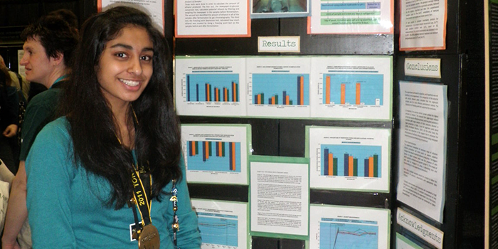 A student standing in front of a science fair display board