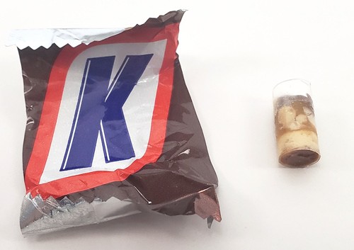 The candy core sample in a straw next to a Snickers® wrapper.