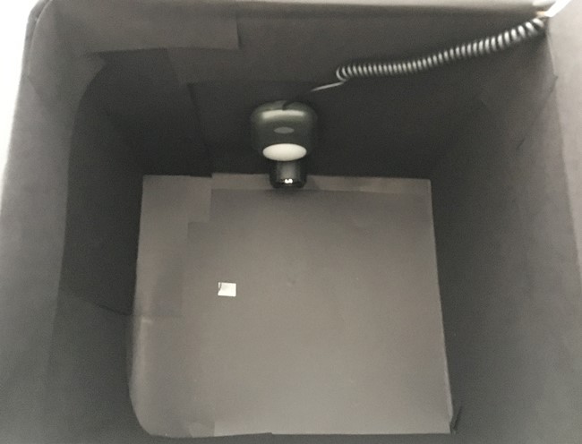 Tape reflecting light from a flashlight which is lighting up the inside of a black box.