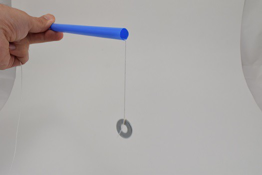 A washer hanging by a string that is strung through a blue straw