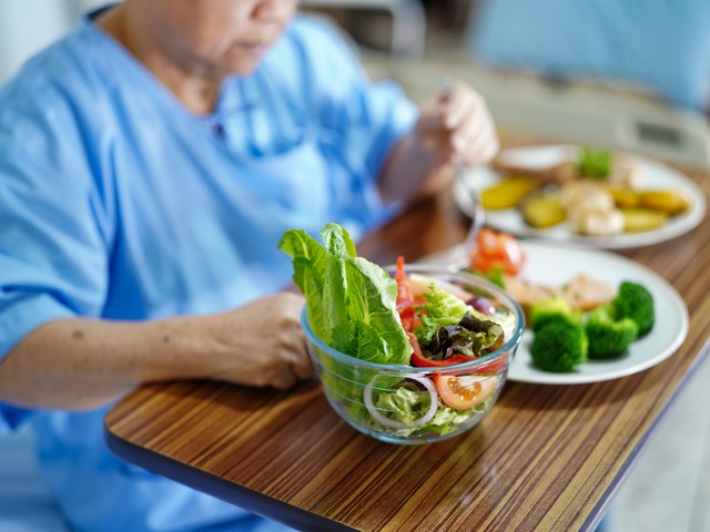 elderly patient eating healthy food in hospital room