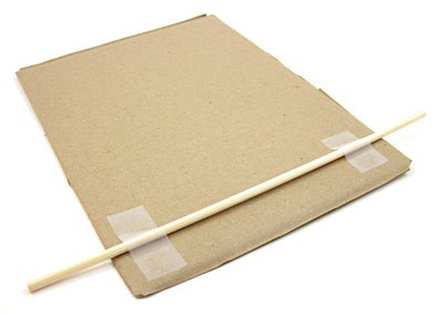 A wooden skewer taped across the width of a rectangular cardboard sheet