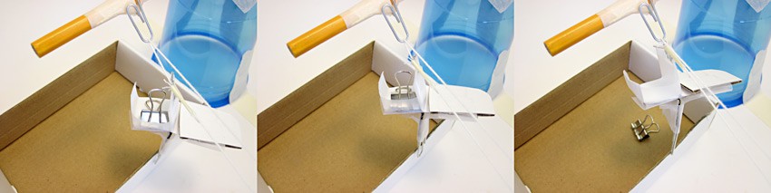 A mini binder clip falls from a paper chair that is attached to a simple string pulley