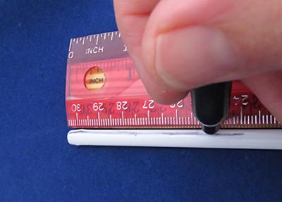 A straight line is marked along the length of a plastic straw using a pen and ruler