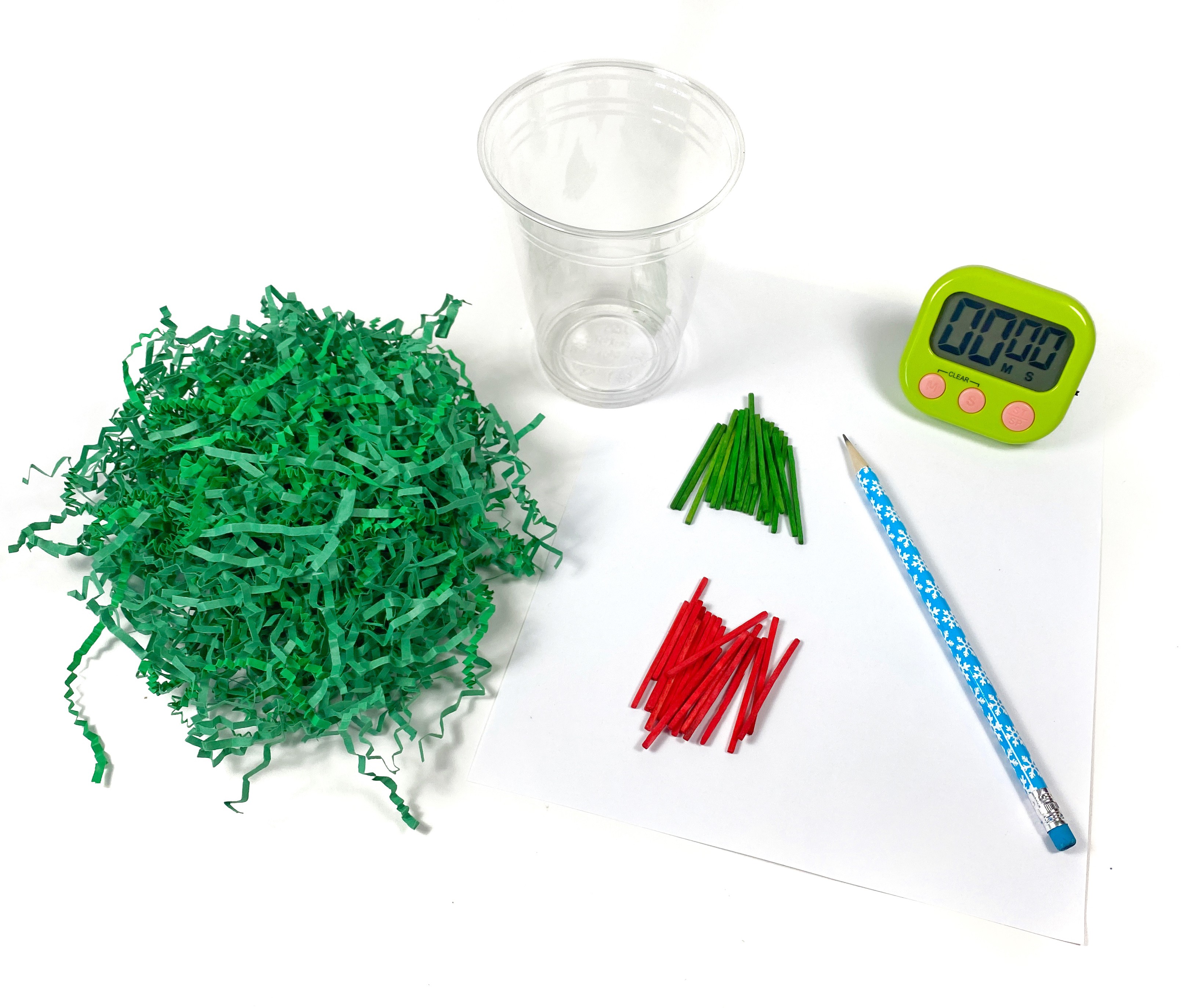 Green shredded paper, red and green matchsticks, a pencil, a sheet of paper, and a timer on a table.
