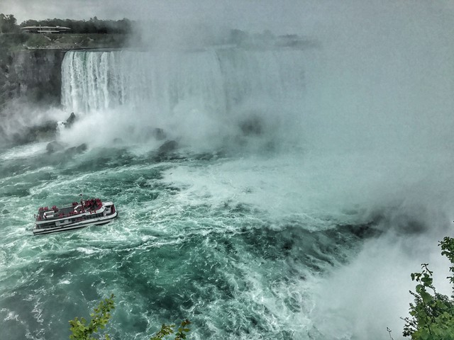 boat in waves near waterfall