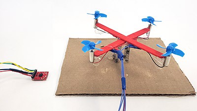 Mini popsicle stick drone next to an accelerometer 