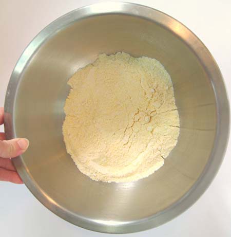 Flour, cornmeal, sugar and baking powder mixed in a metal bowl