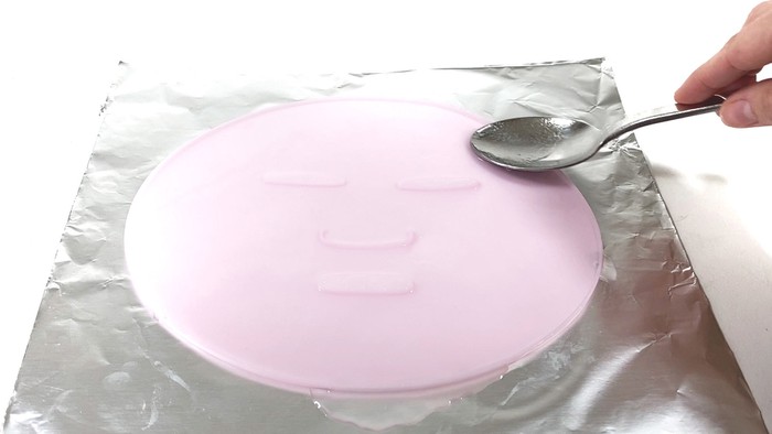A face mask mold filled with liquid on a an aluminum sheet. 