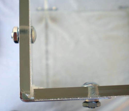 Screws and nuts are used to attach a corner bracket to the walls of a Plexiglas box