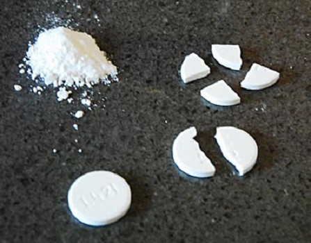 A whole Alka-seltzer tablet, a second cut in half, a third cut in quarters, and a fourth ground into a powder.