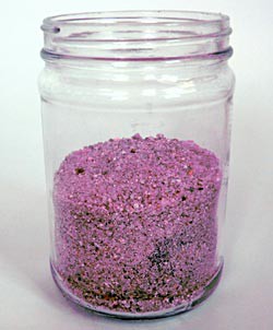 Pink sand and iron filings are mixed in a glass jar