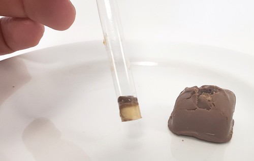 A cylindrical core sample that has been removed from a candy bar, inside a clear straw. 