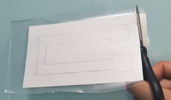 Trimming the edges of the vinyl on the glossy tattoo backing paper. 