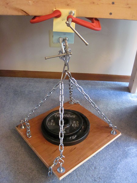 One end of a interlaced paper pad is clamped to a wood frame while weighted plates are placed on the bottom end