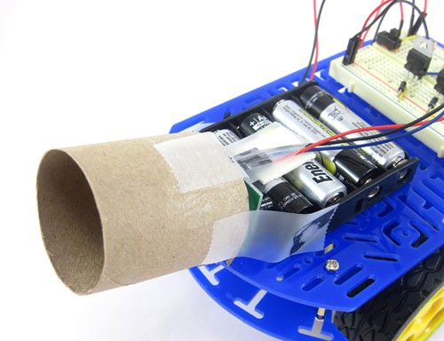 A small cardboard tube is taped over a PIR sensor that is attached to the front of a robot chassis