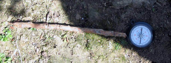 A wooden stick lies perpendicular to the arrow of a compass point north