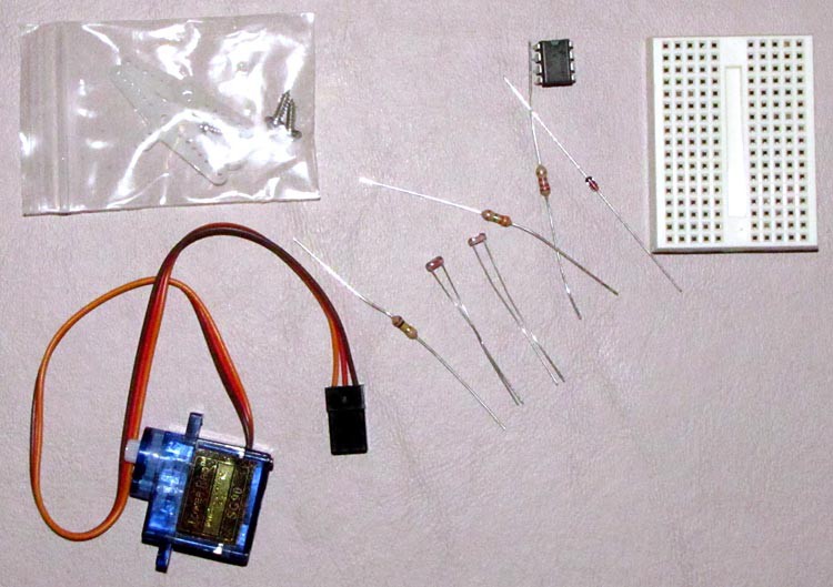 A servo motor, servo horn, three resistors, two photoresistors, a diode, 555 timer chip and a breadboard