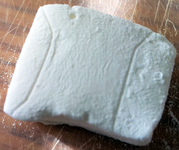 A large homemade marshmallow ready to be cut into pieces