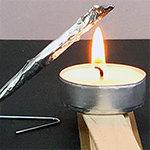 Matchstick rocket made from aluminum foil and placed by a small tea light candle