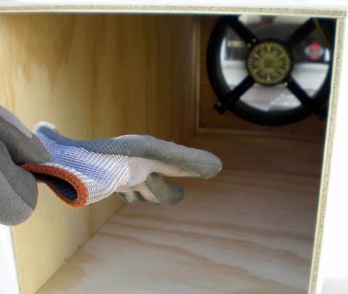 Photo of a glove being pulled towards a fan at the end of a wooden box