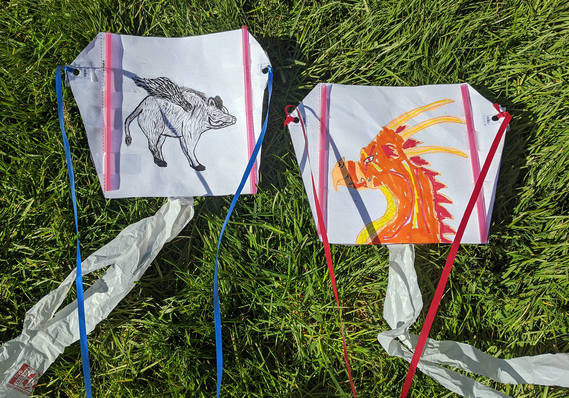 Two homemade paper kites in the grass