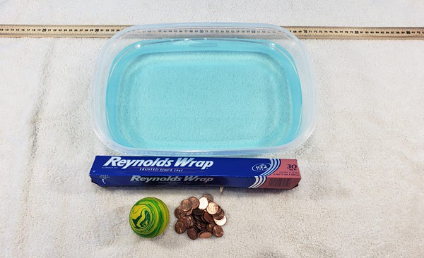 A meter stick, plastic container, water, aluminum foil, pennies and a rubber ball