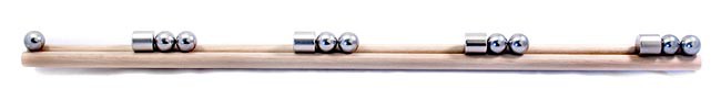 Four magnets each with two metal balls attached to one end are spaced evenly apart on a wooden rail in