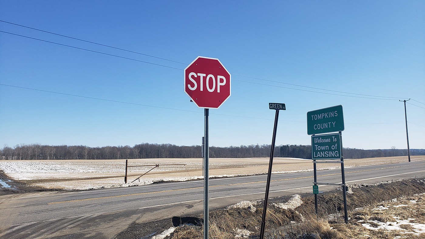 A stop sign on a country road with blue sky in the background.