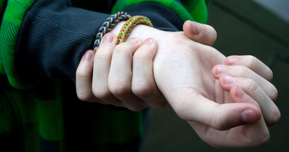 Young person taking radial pulse, fingers on wrist