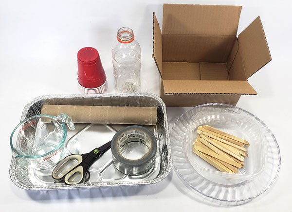 Plastic cups, a plastic bottle, a cardboard and tube, scissors, tape, popsicle sticks, a measuring cup and shallow containers