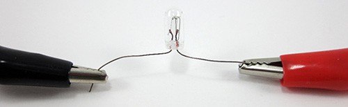 Red and black alligator clips connected to a bulb with clear housing