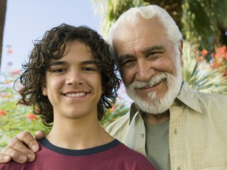 A grandfather with one arm around his teenage grandson's shoulders.